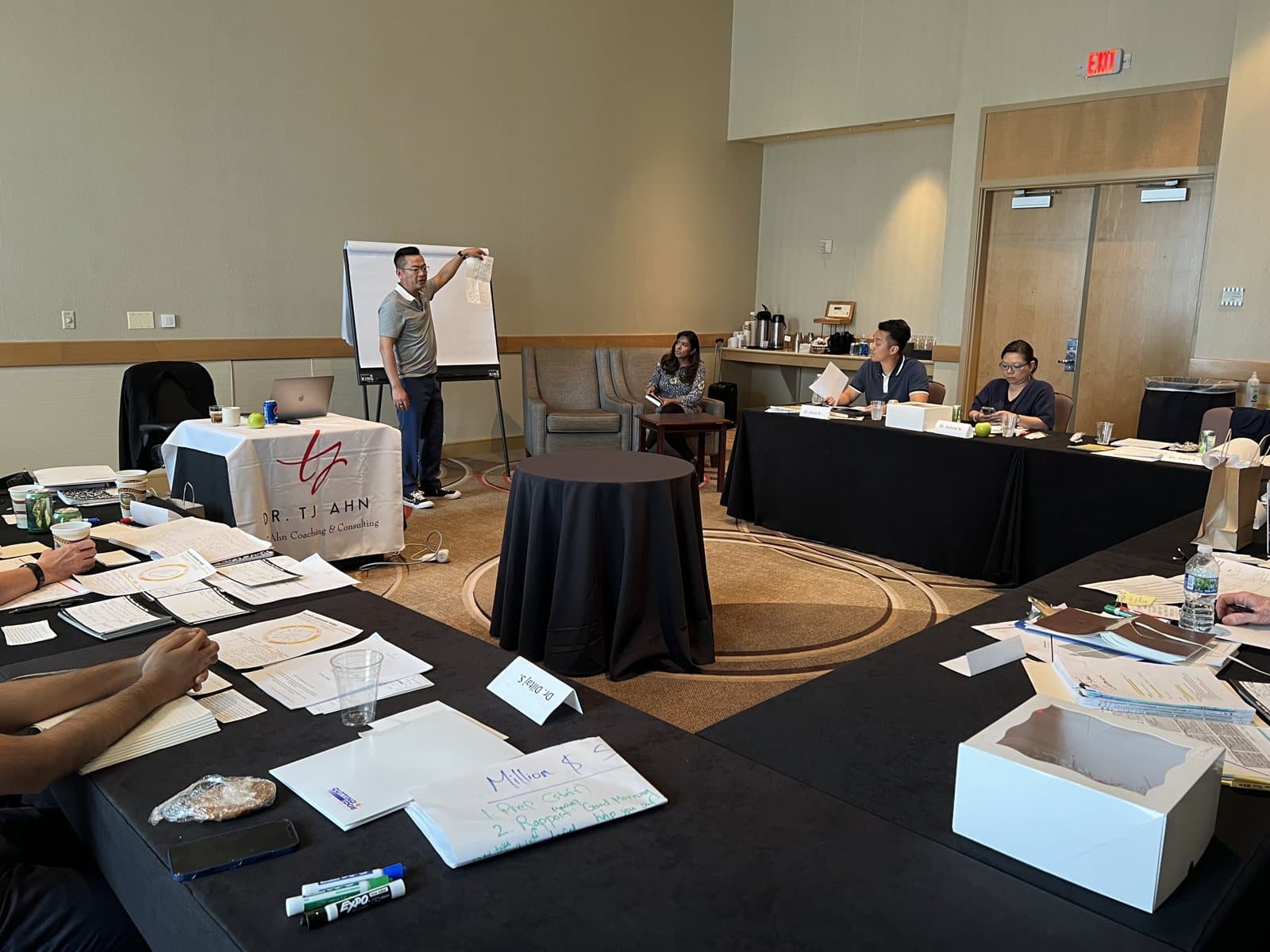 Dr. Ahn teaching at the flip chart while practice owners work at their tables